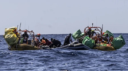 Personal de rescate del barco humanitario Ocean Viking de SOS Mediterranee ayuda a migrantes a evacuar un bote de goma parcialmente desinflado en el Mar Mediterráneo